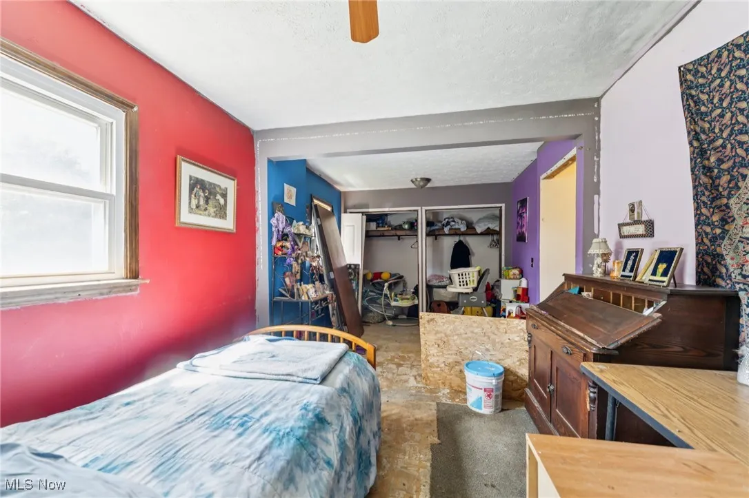Bedroom with a closet, a textured ceiling, and a ceiling fan