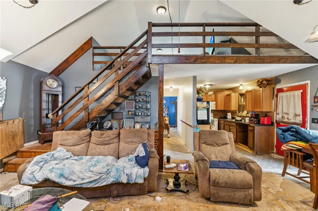 Living room with stairs, high vaulted ceiling, and beamed ceiling