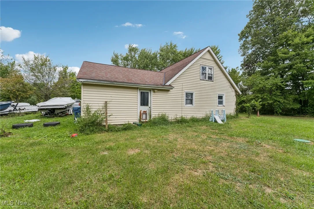 Back of house with a yard and a shingled roof