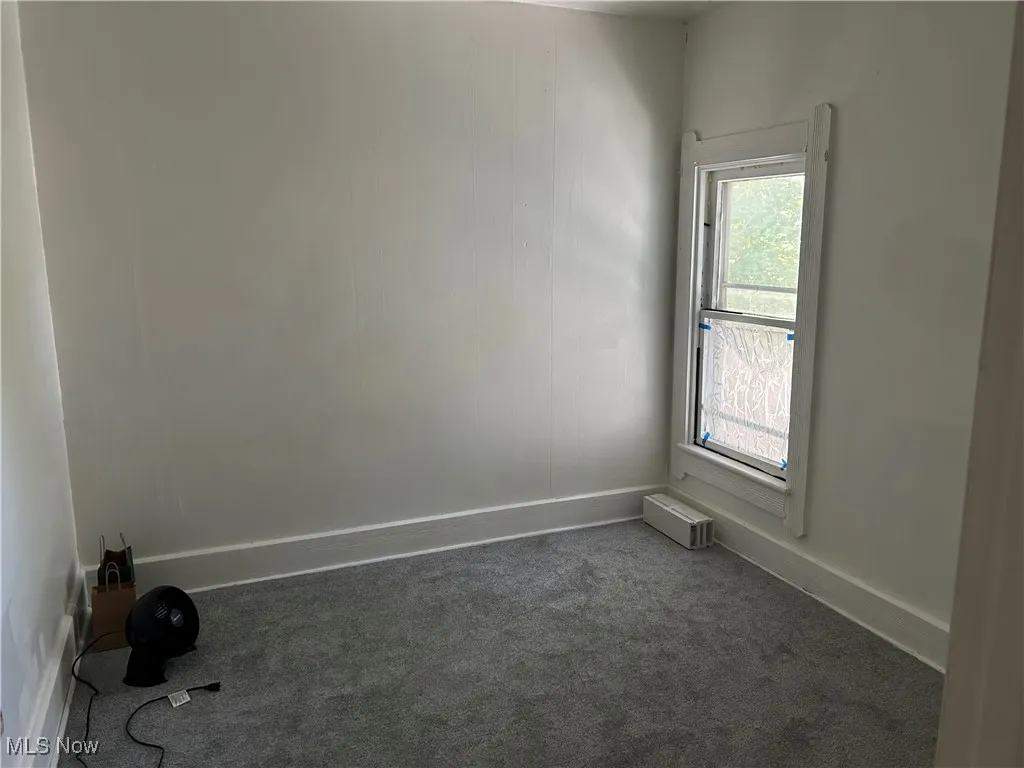 Spare room with baseboards and dark colored carpet