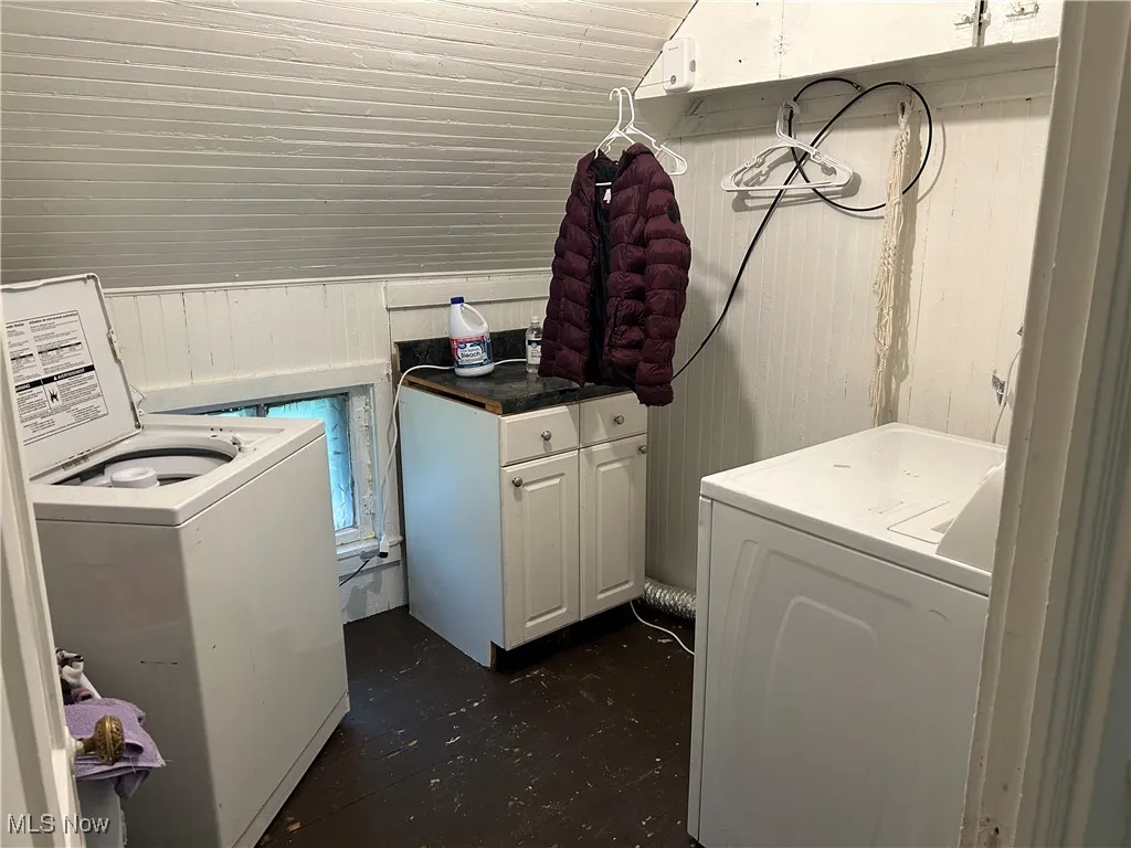 Laundry area featuring wood walls, cabinet space, and dark wood finished floors
