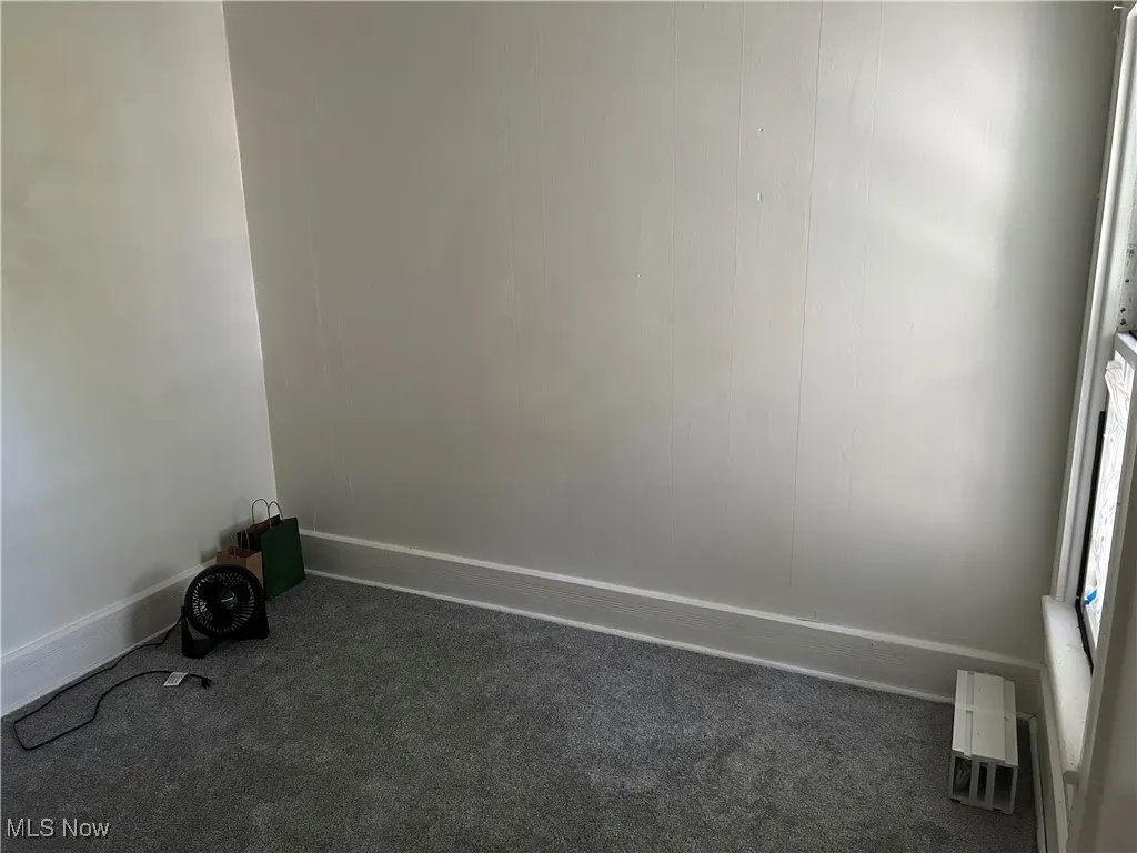 Unfurnished room featuring baseboards and dark colored carpet