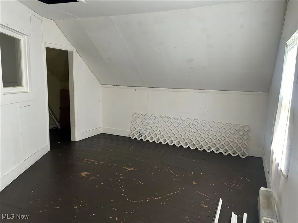 Additional living space with lofted ceiling and dark wood-style floors