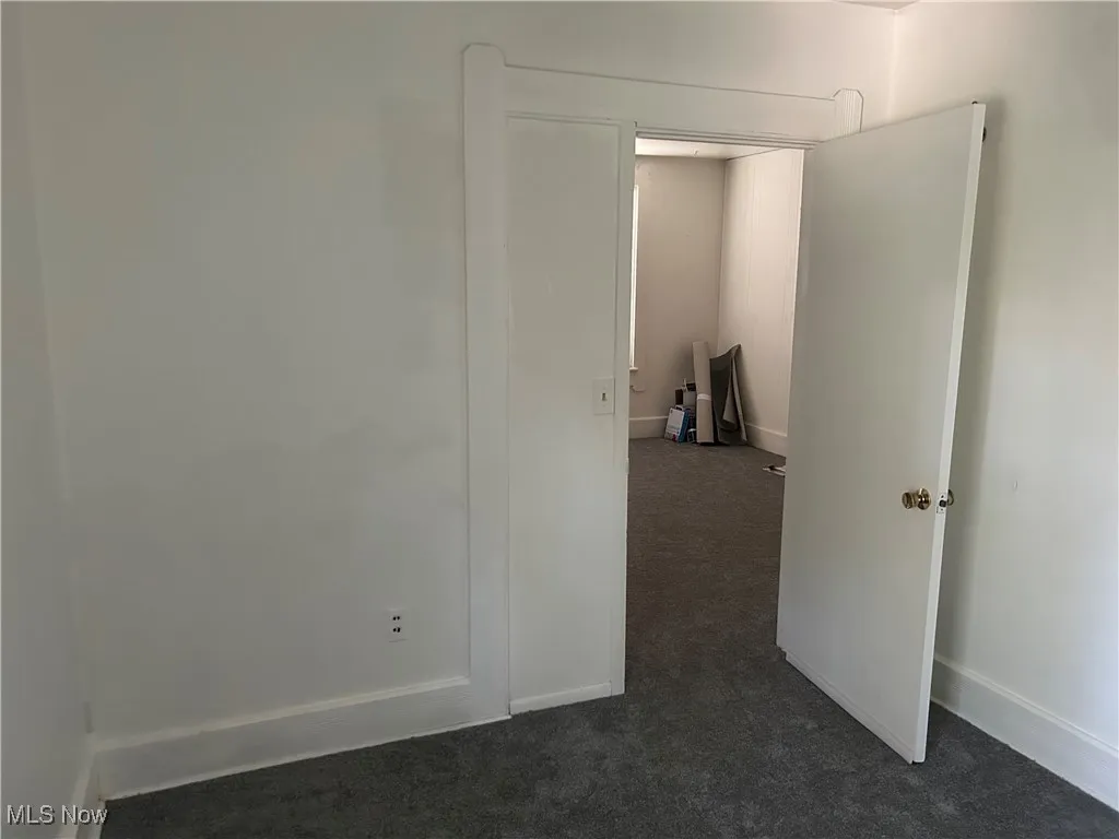 Empty room featuring dark carpet and baseboards