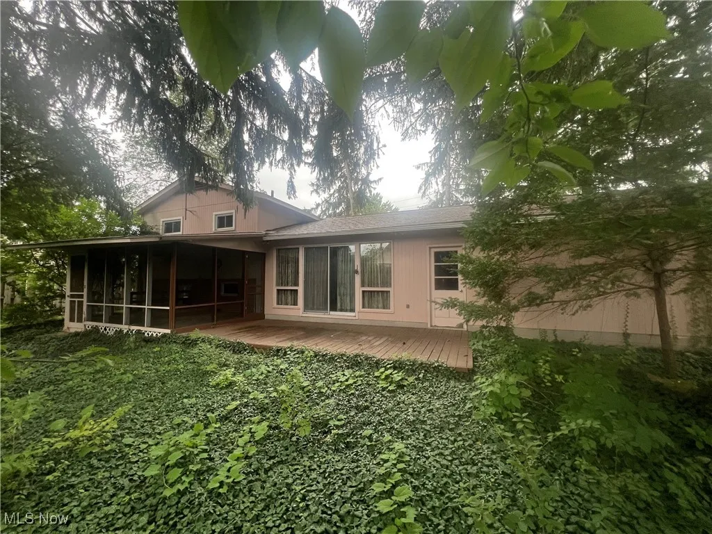 Back of house featuring a deck, a sunroom, and a shingled roof