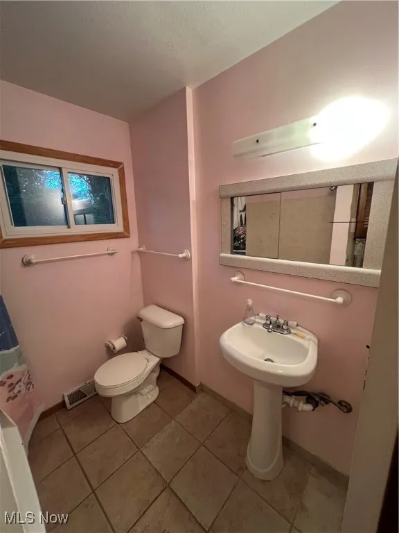 Bathroom featuring light tile patterned floors and a textured ceiling