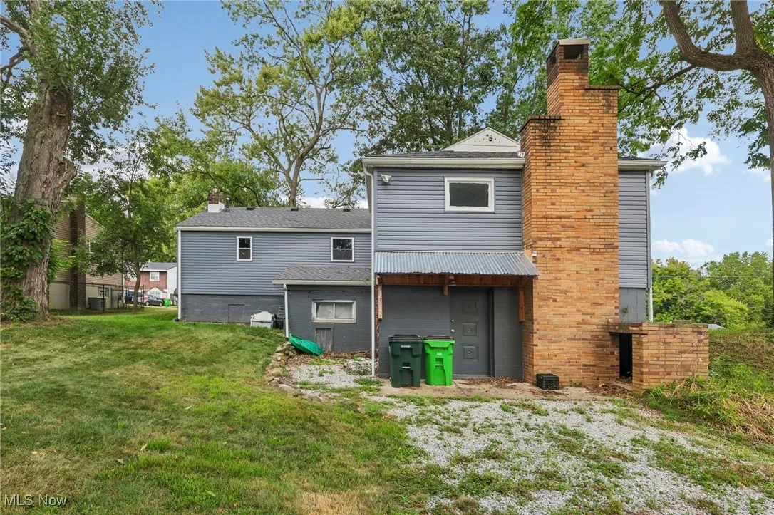 Back of property with a chimney and a lawn