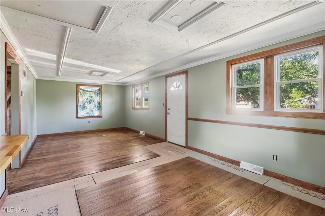 Entrance foyer featuring hardwood / wood-style flooring, crown molding, and a textured ceiling