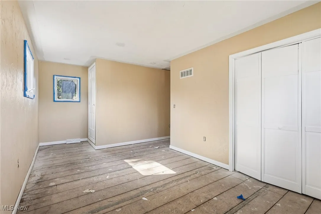 Unfurnished bedroom with baseboards and hardwood / wood-style flooring
