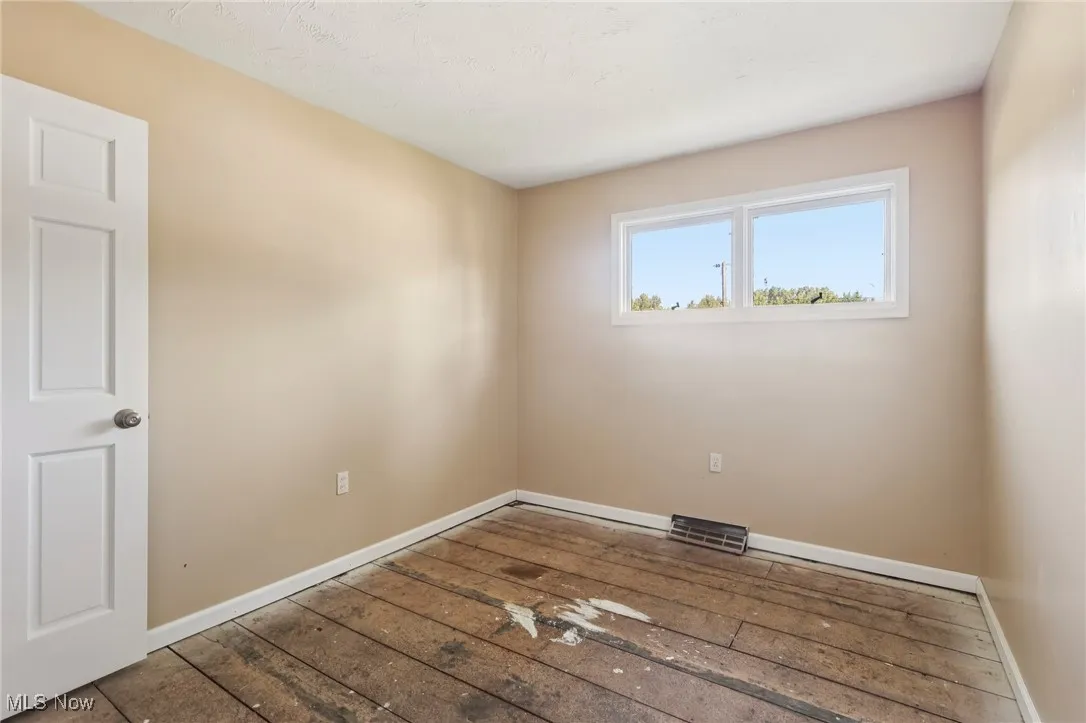 Spare room with baseboards and hardwood / wood-style floors