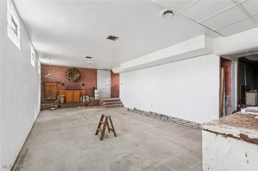 Unfurnished living room featuring concrete flooring and brick wall