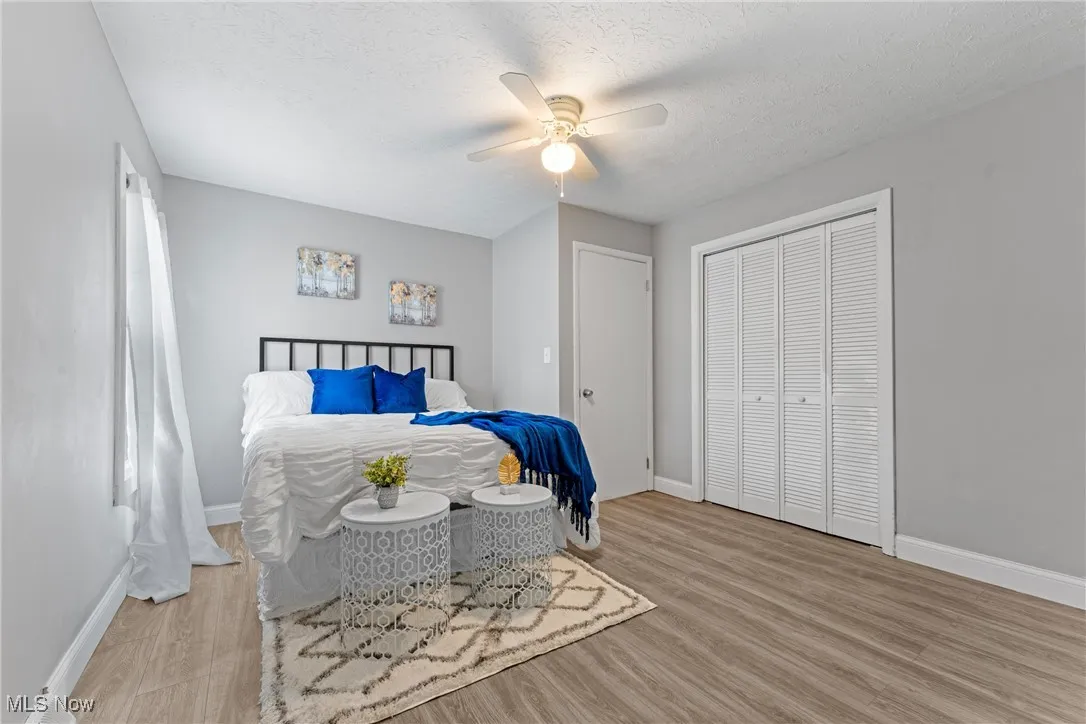 Bedroom featuring light wood-style floors, a ceiling fan, a textured ceiling, and a closet