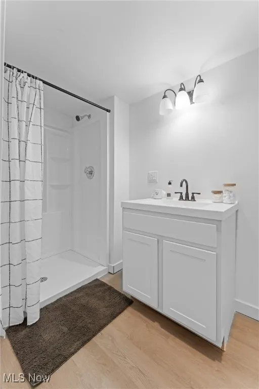 Full bathroom featuring a shower stall, light wood finished floors, and vanity