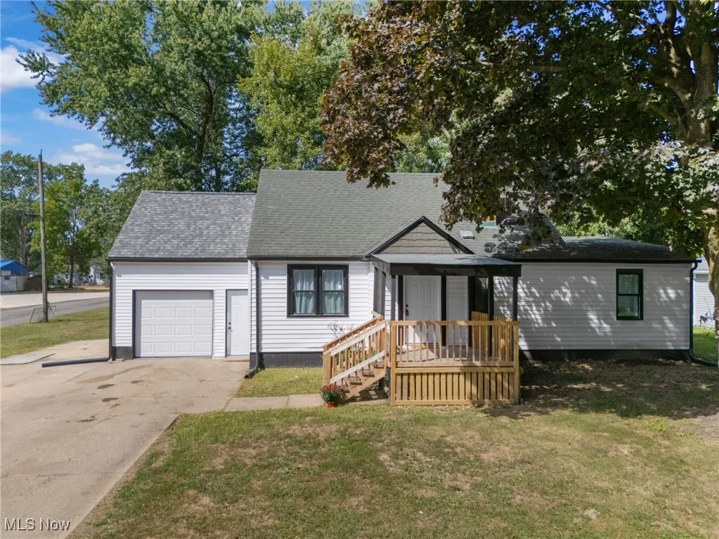 View of front of home featuring a shingled roof, driveway, an attached garage, and a front yard