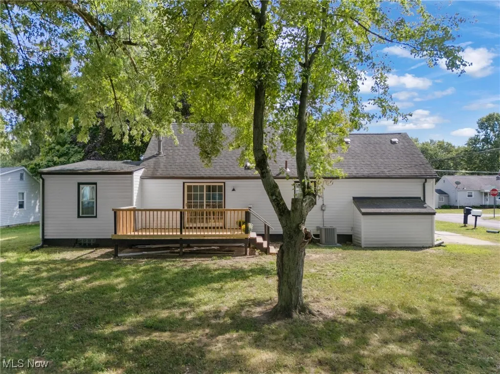 Back of house featuring a yard, roof with shingles, and a deck
