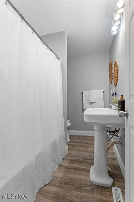 Full bathroom with dark wood-style floors and curtained shower
