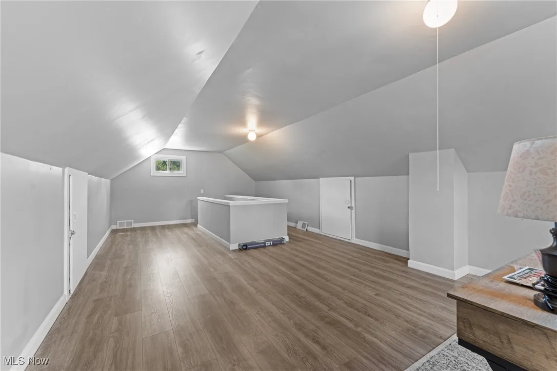 Additional living space with light wood-style flooring and vaulted ceiling