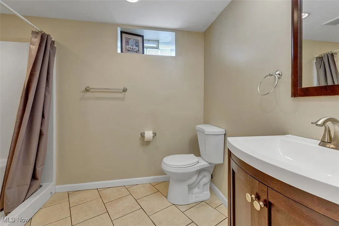 Full bath featuring vanity, light tile patterned floors, and a shower stall