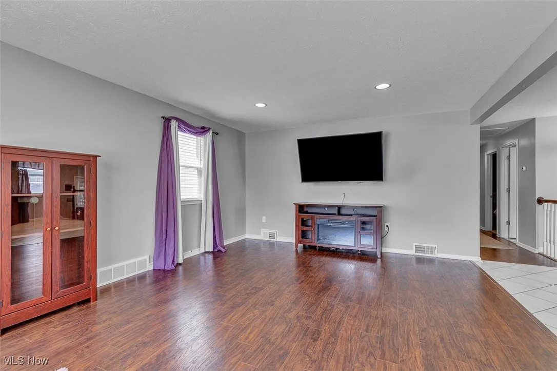 Unfurnished living room featuring wood finished floors, a textured ceiling, and recessed lighting