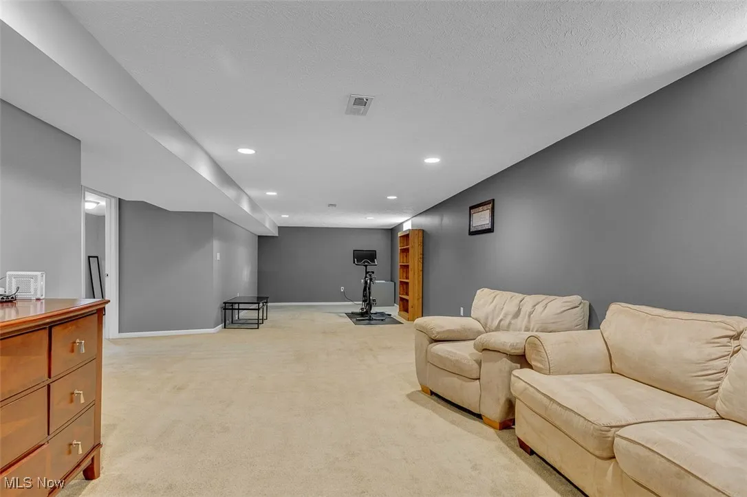 Living room with light carpet, recessed lighting, and a textured ceiling