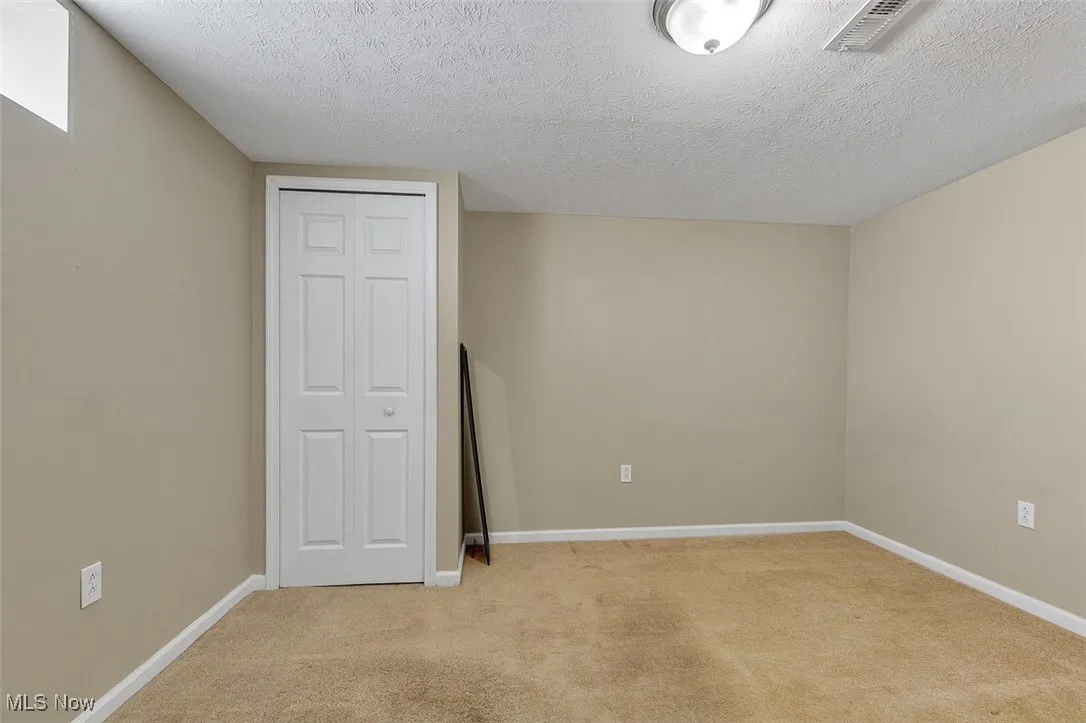 Unfurnished bedroom with light colored carpet, a textured ceiling, and a closet
