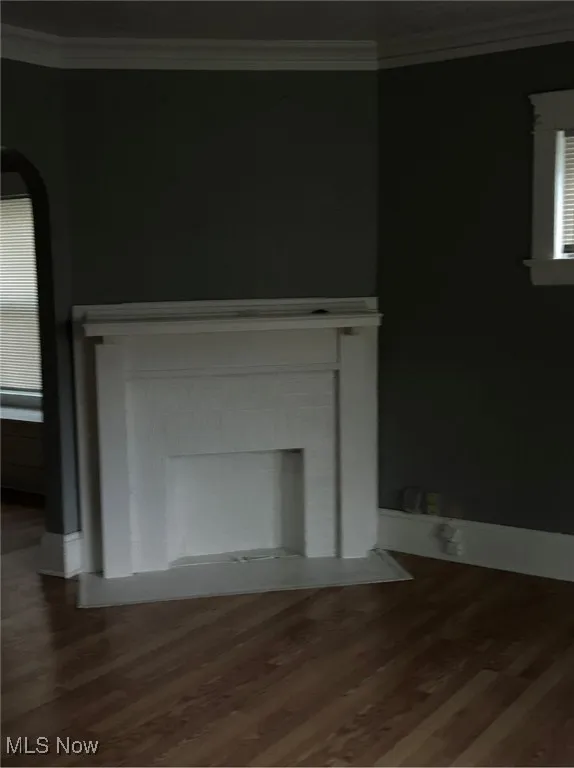 Detailed view of crown molding, wood finished floors, and a fireplace with flush hearth