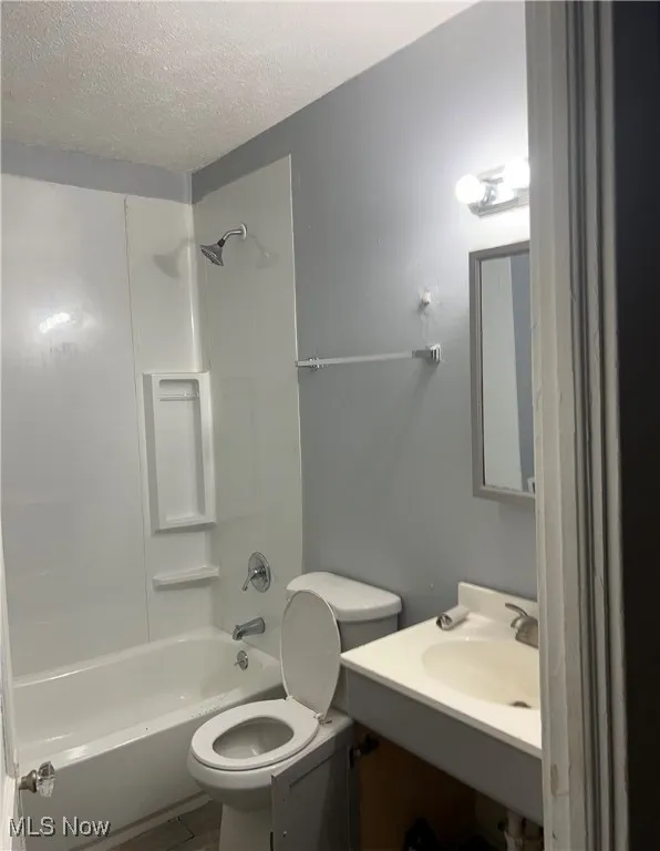 Full bath featuring bathtub / shower combination, vanity, and a textured ceiling