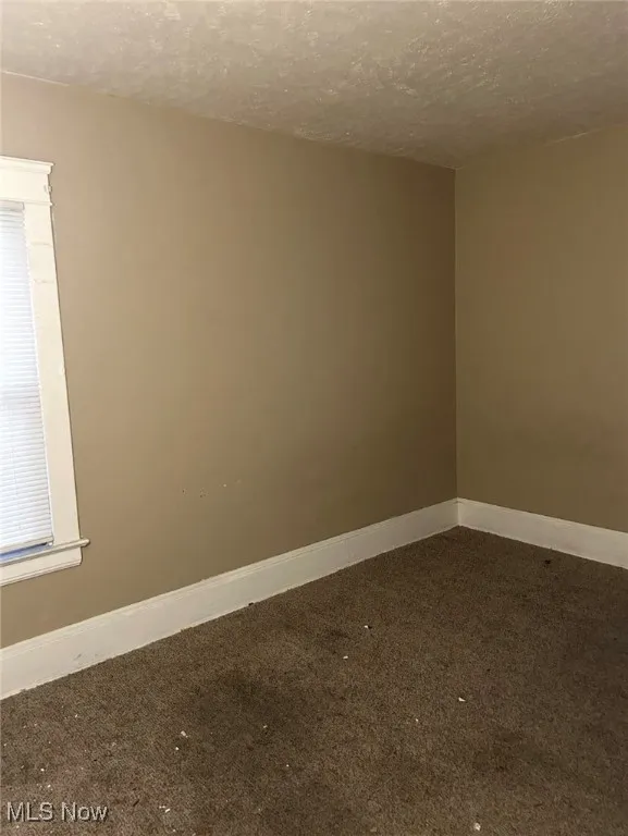 Spare room featuring a textured ceiling and carpet floors