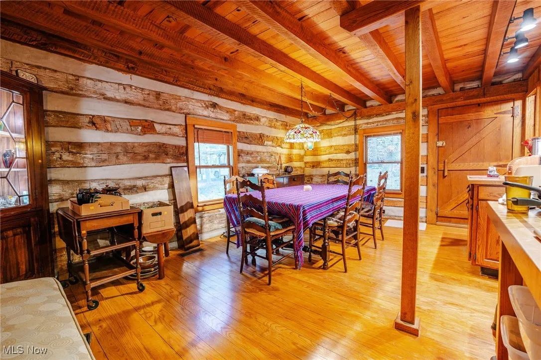 Dining area featuring light wood finished floors, wood walls, and a wooden ceiling with exposed beams