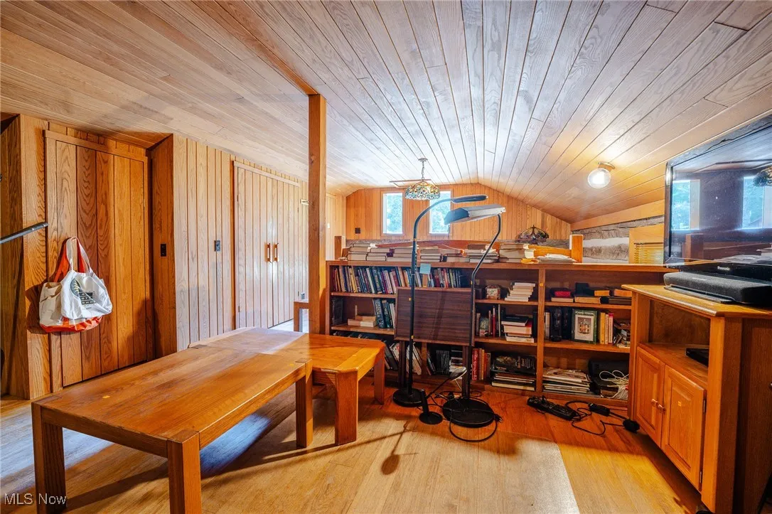 Office area featuring wooden walls, light wood-type flooring, vaulted ceiling, and wood ceiling