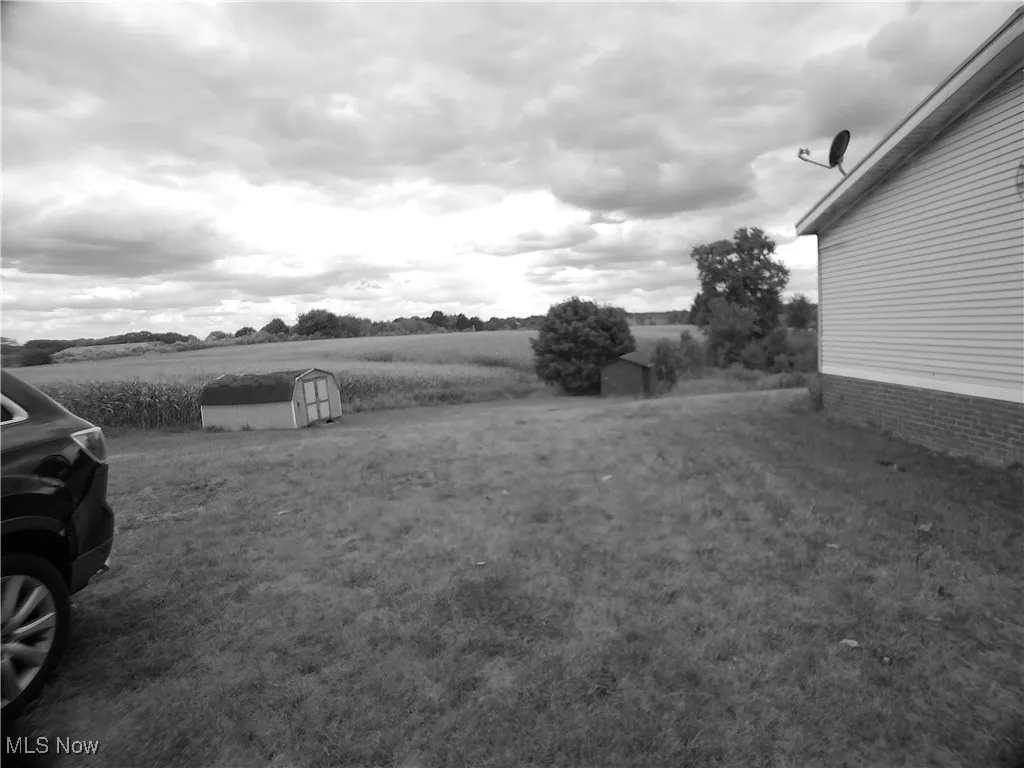 View of yard with a storage unit and a rural view