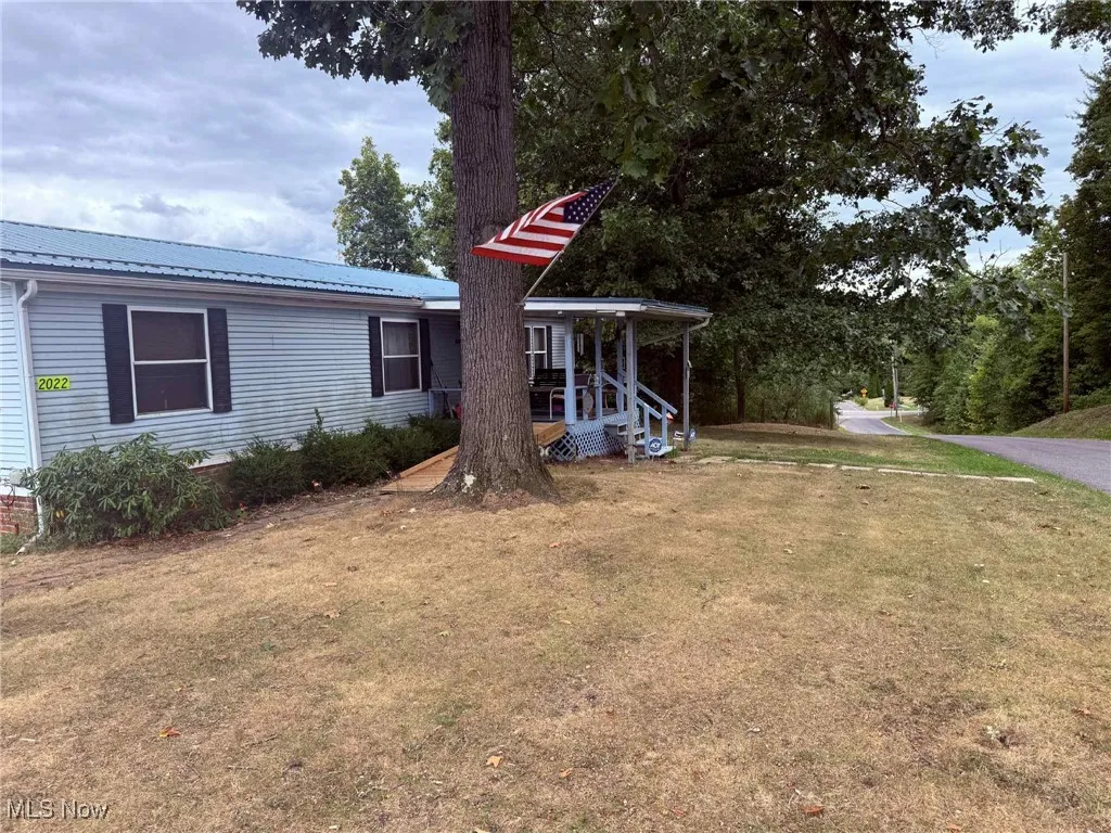 View of grassy yard featuring covered porch