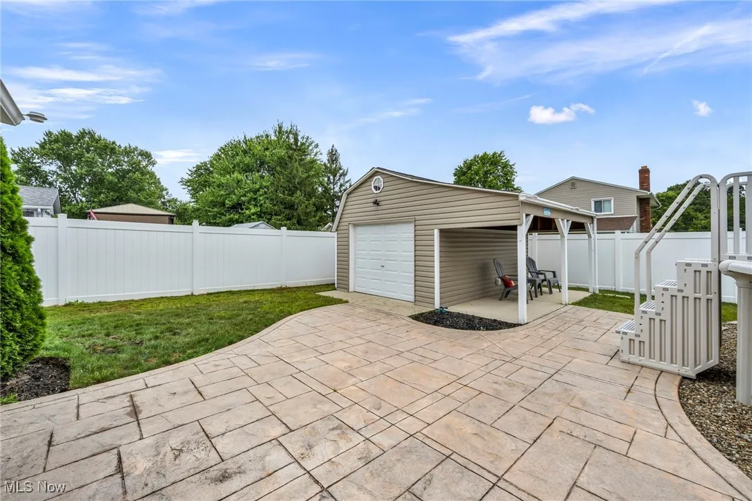 Fenced backyard with a patio area, an outdoor structure, and a garage