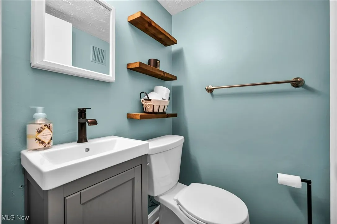 Half bath with vanity and a textured ceiling