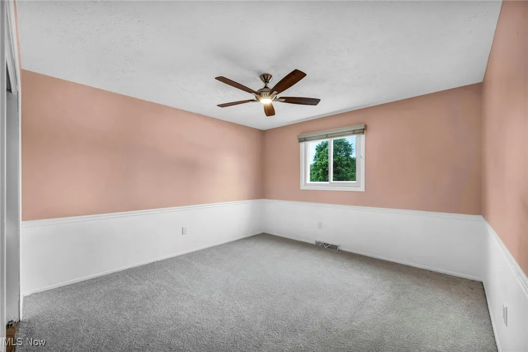Empty room featuring carpet floors, ceiling fan, and a textured ceiling