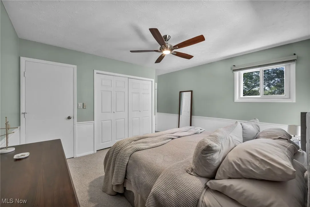 Bedroom featuring carpet flooring, a textured ceiling, a closet, and ceiling fan