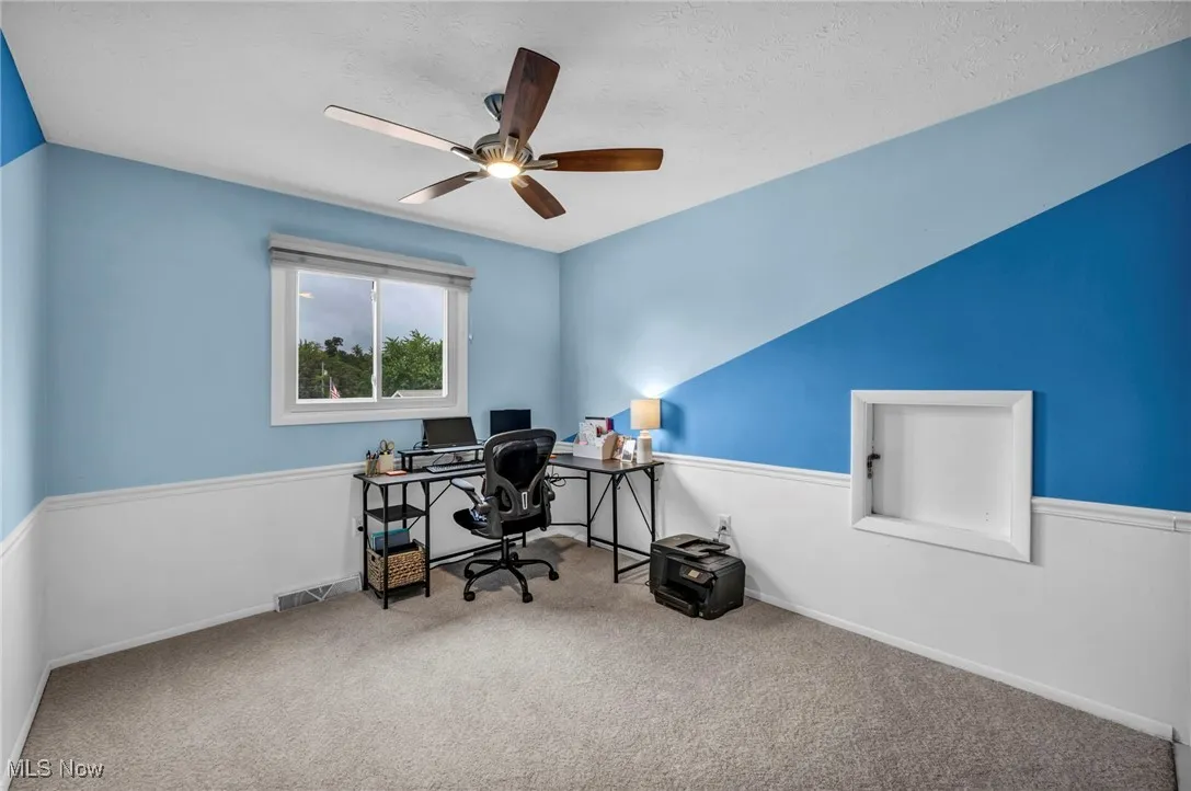 Carpeted office with a textured ceiling and ceiling fan