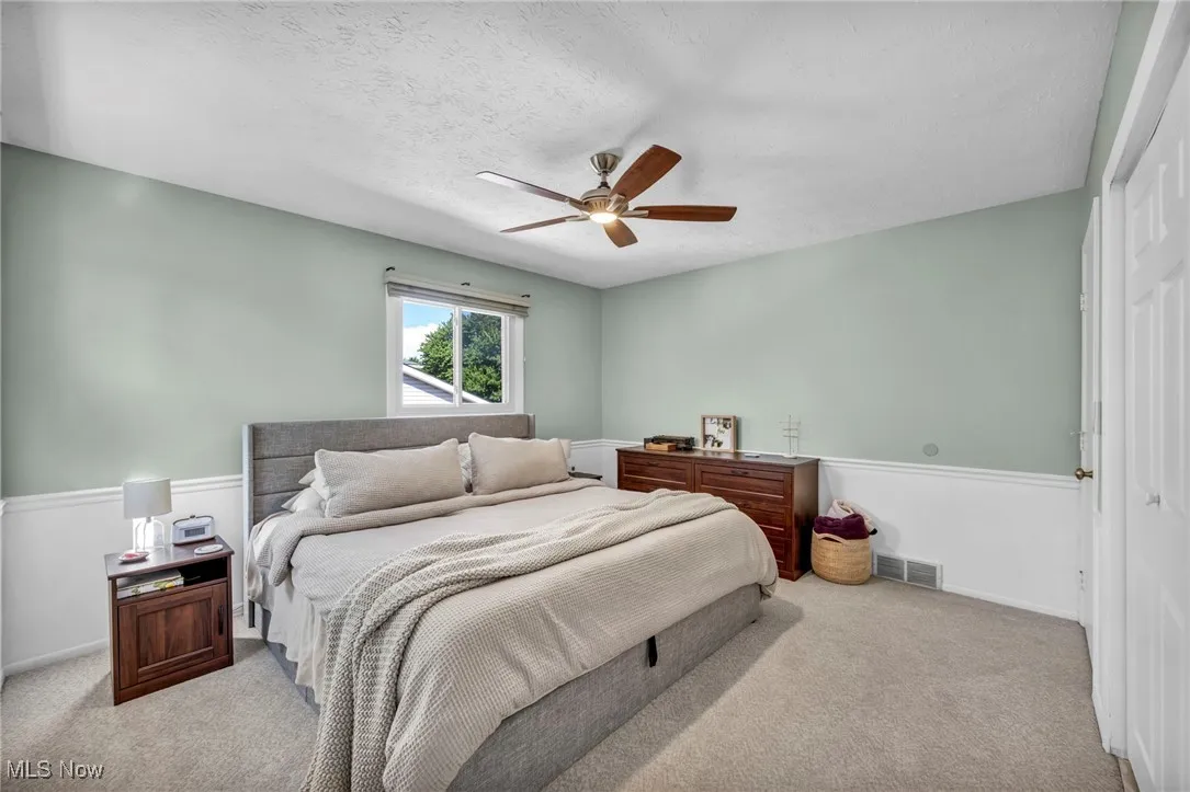 Bedroom with carpet flooring, a textured ceiling, and ceiling fan