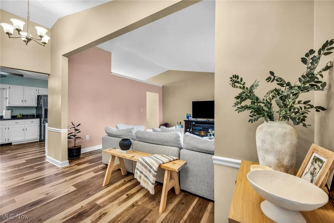Living area featuring vaulted ceiling, light wood finished floors, and a chandelier