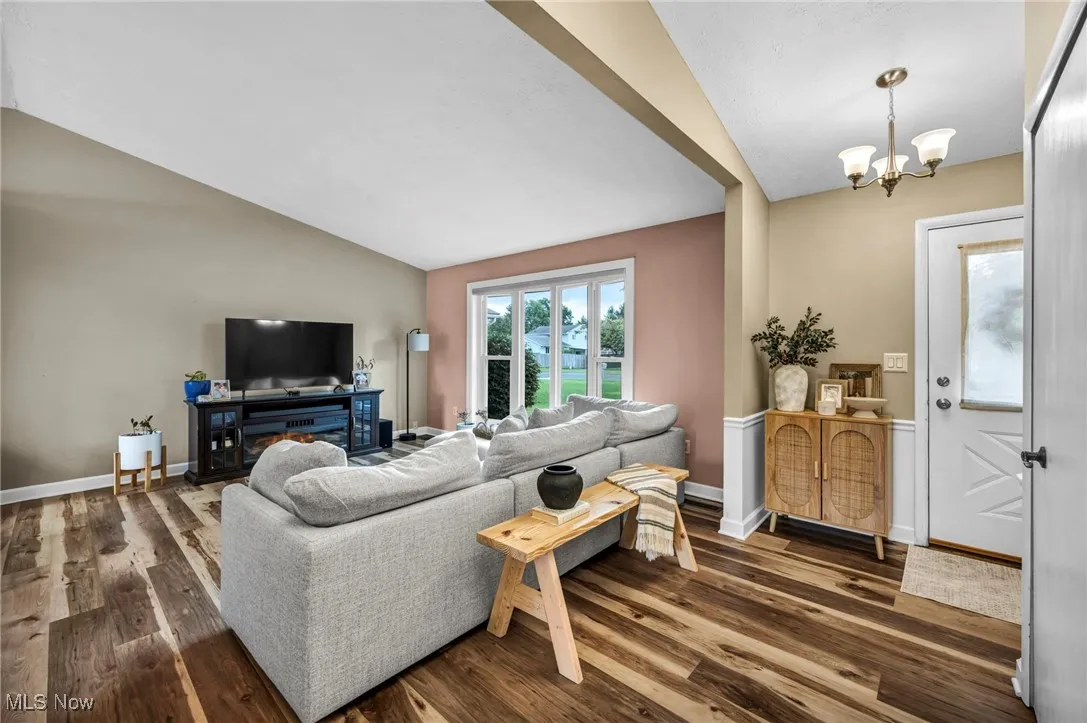 Living room with lofted ceiling, dark wood-type flooring, and a chandelier