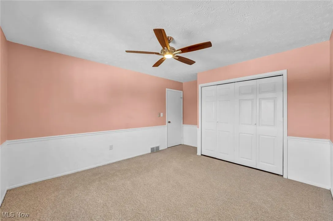 Unfurnished bedroom with carpet, a closet, ceiling fan, and a textured ceiling