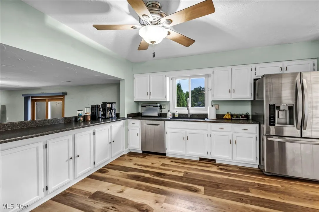 Kitchen with white cabinets, stainless steel appliances, light wood-style flooring, and a ceiling fan