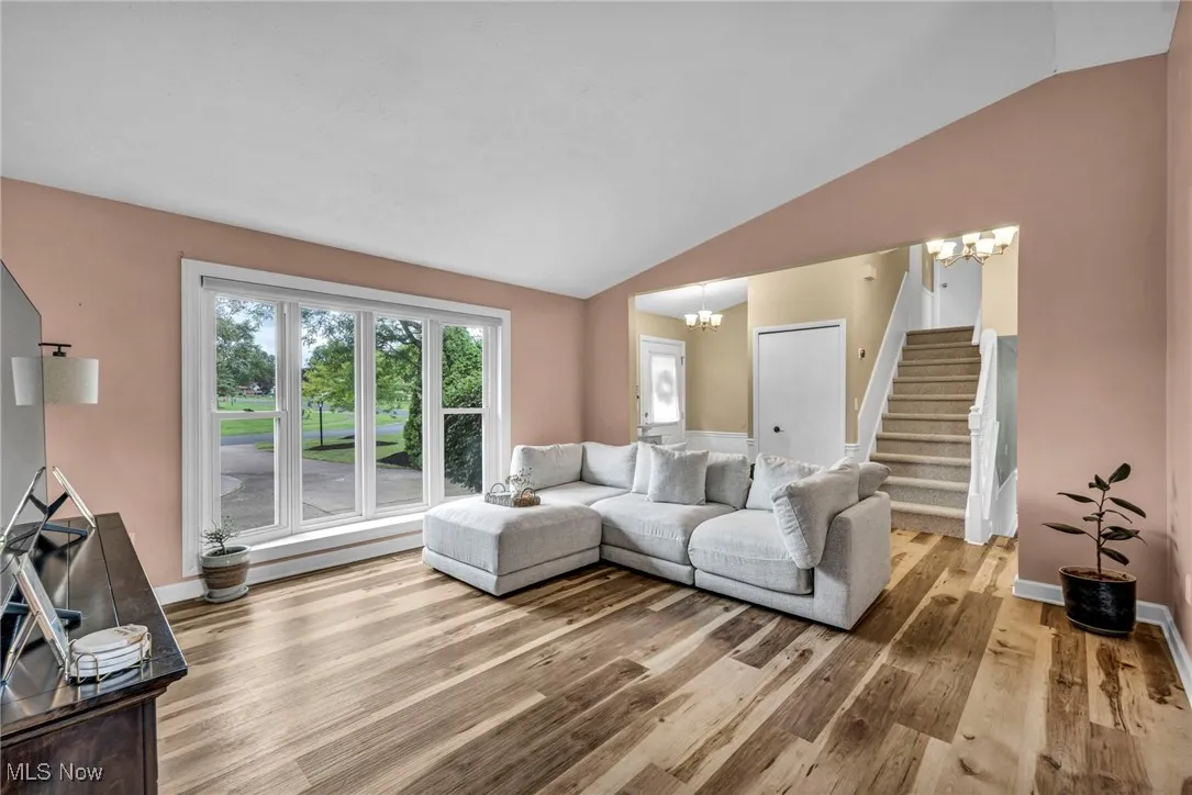 Living area featuring a chandelier, stairway, lofted ceiling, and light wood finished floors