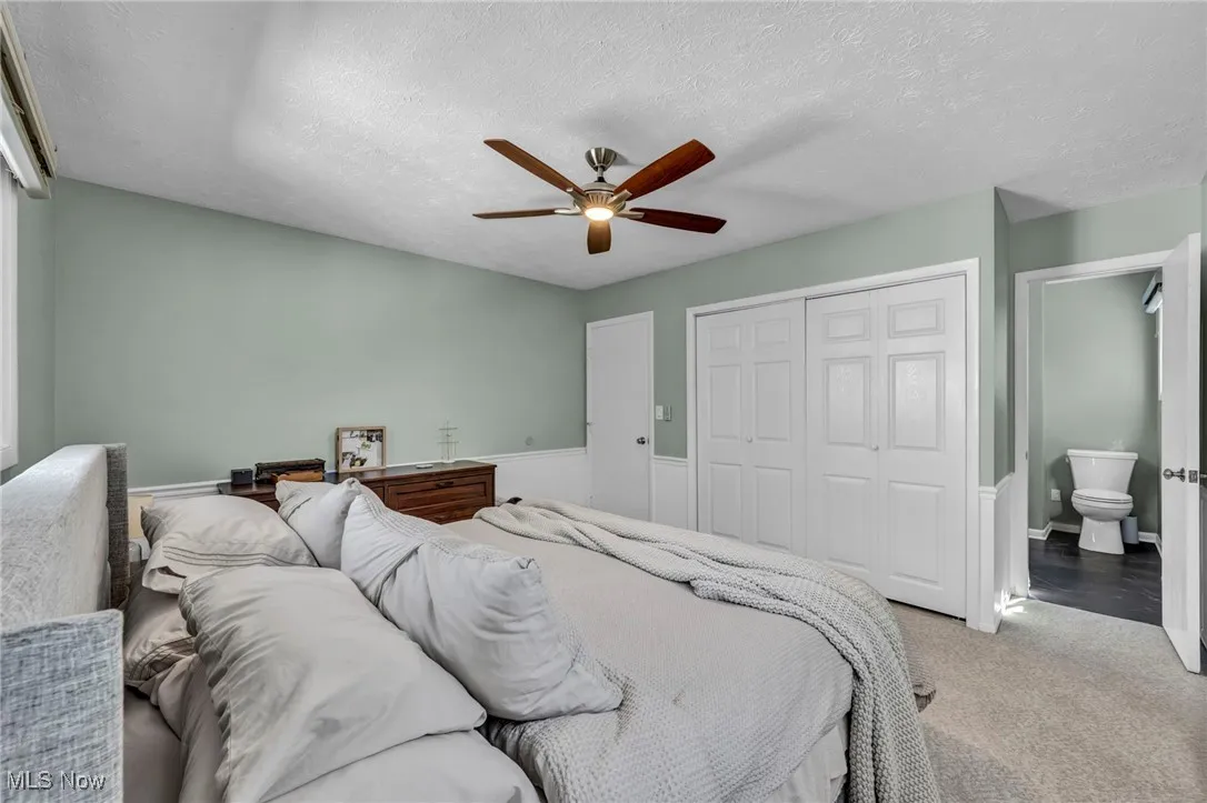 Carpeted bedroom featuring a textured ceiling, a closet, and ceiling fan