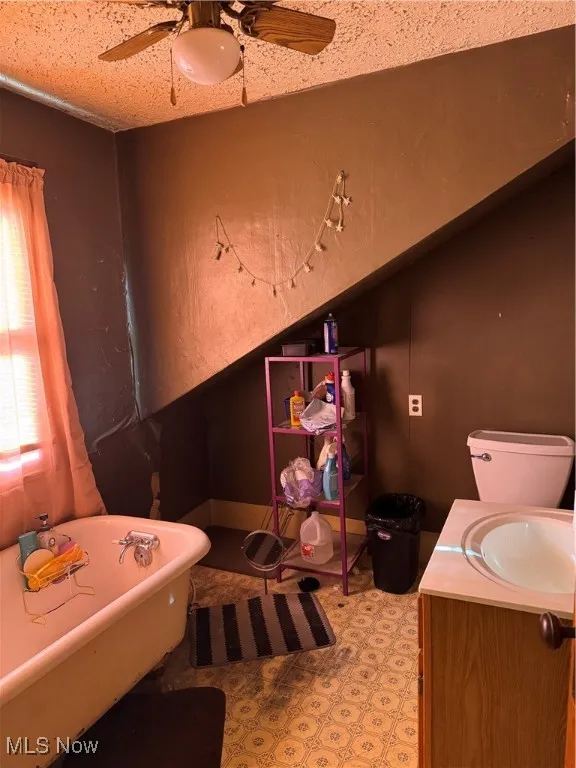 Full bathroom with a freestanding bath, vanity, and ceiling fan