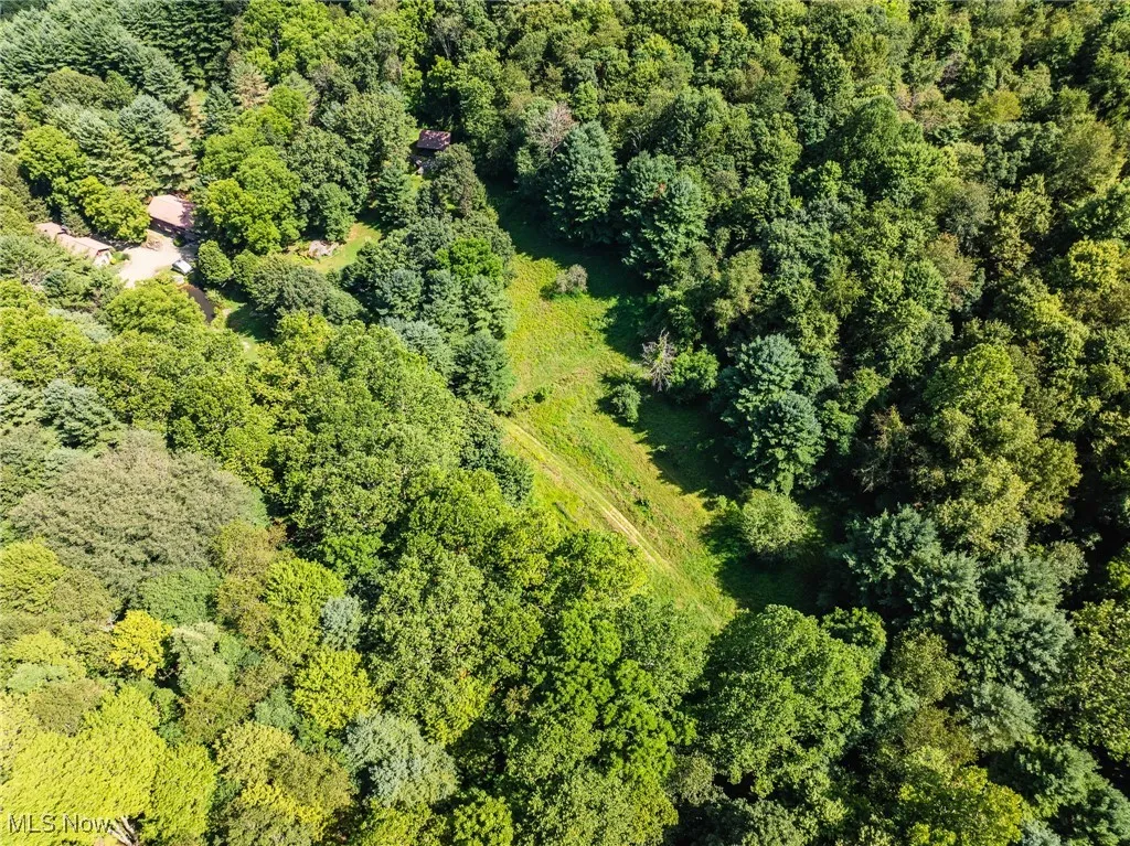 Aerial view of property and surrounding area with a heavily wooded area