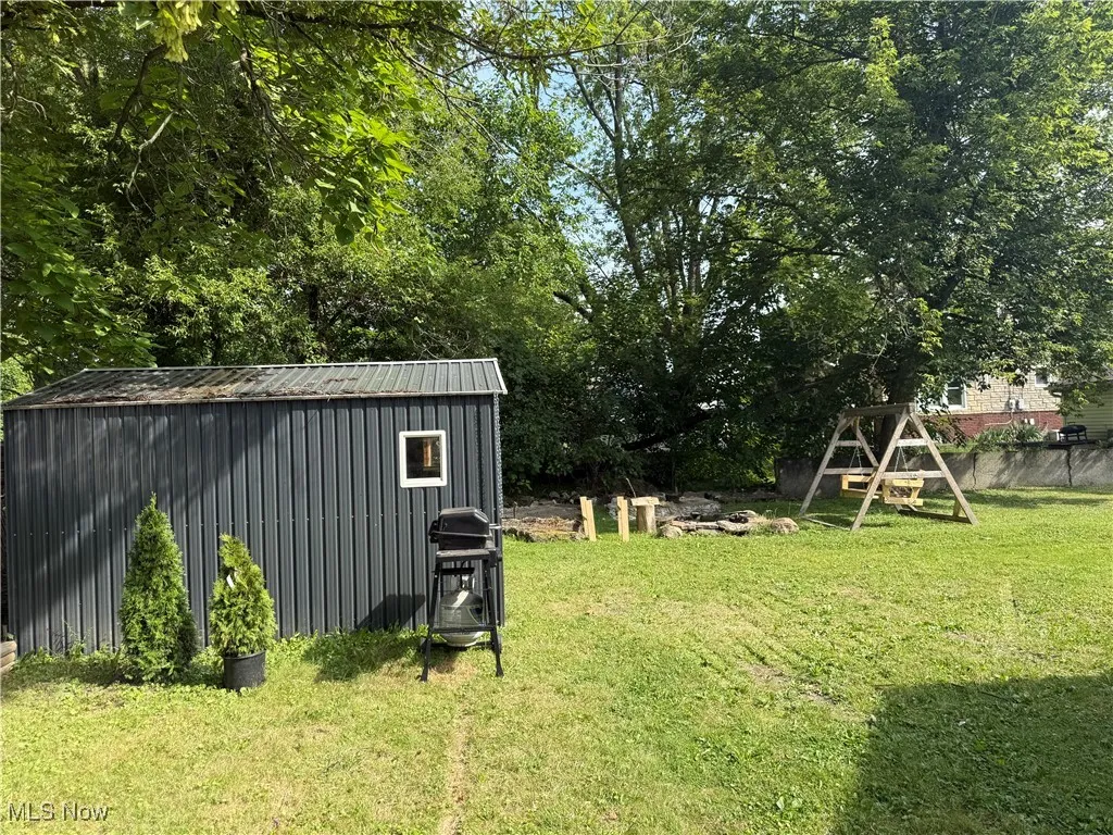 View of yard featuring an outbuilding and view of wooded area