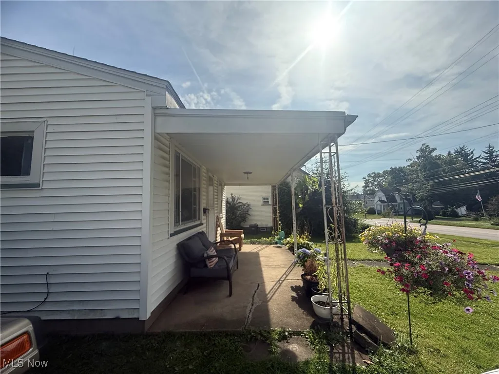 View of property exterior featuring a lawn and covered porch