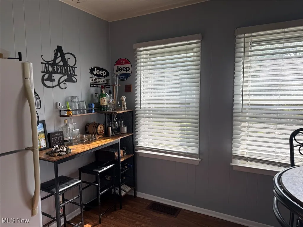 Home office featuring dark wood-style floors, wood walls, and crown molding