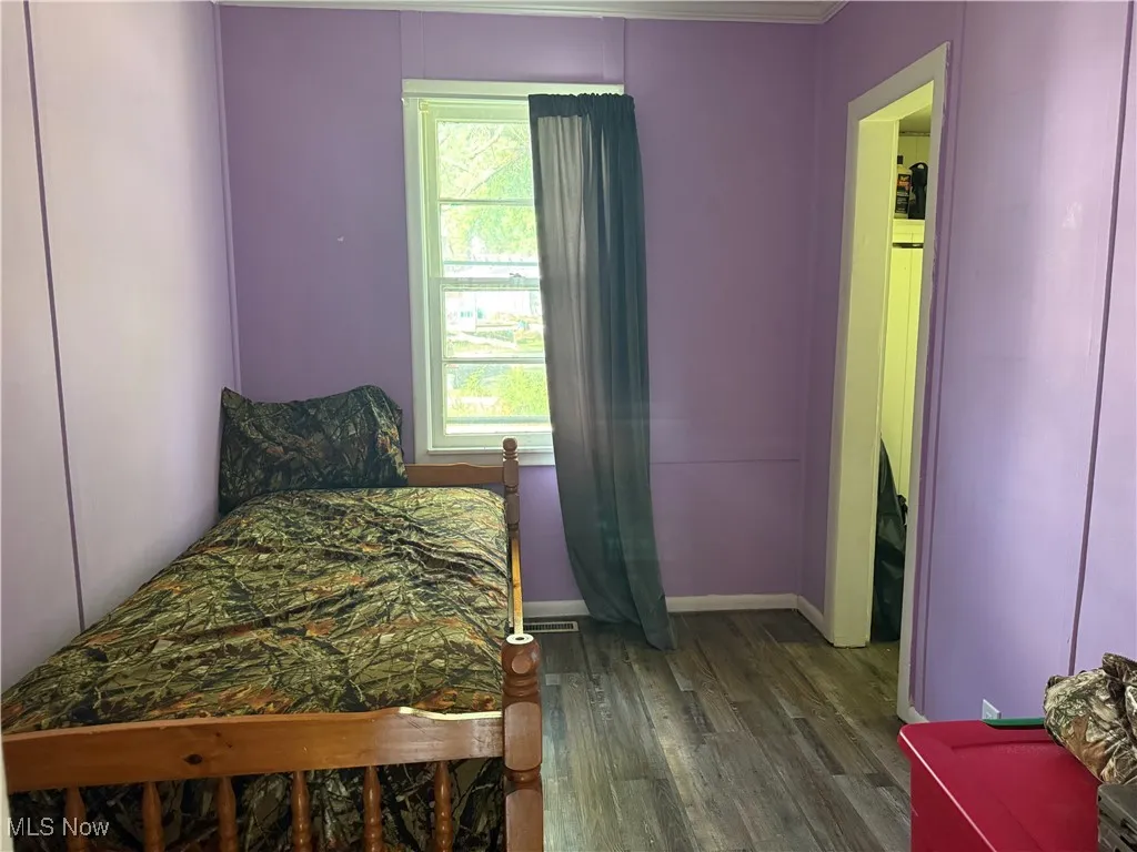 Bedroom with dark wood-style floors and ornamental molding
